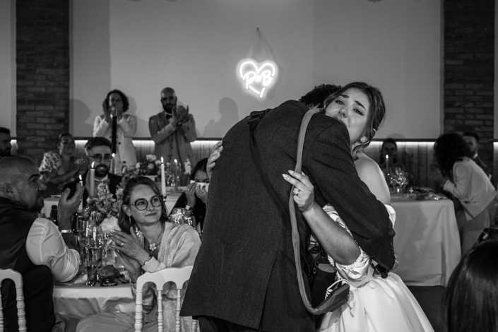Embrassade émue pendant le dîner, en noir et blanc – mariage de Pauline et Boris aux Écuries de Sologne